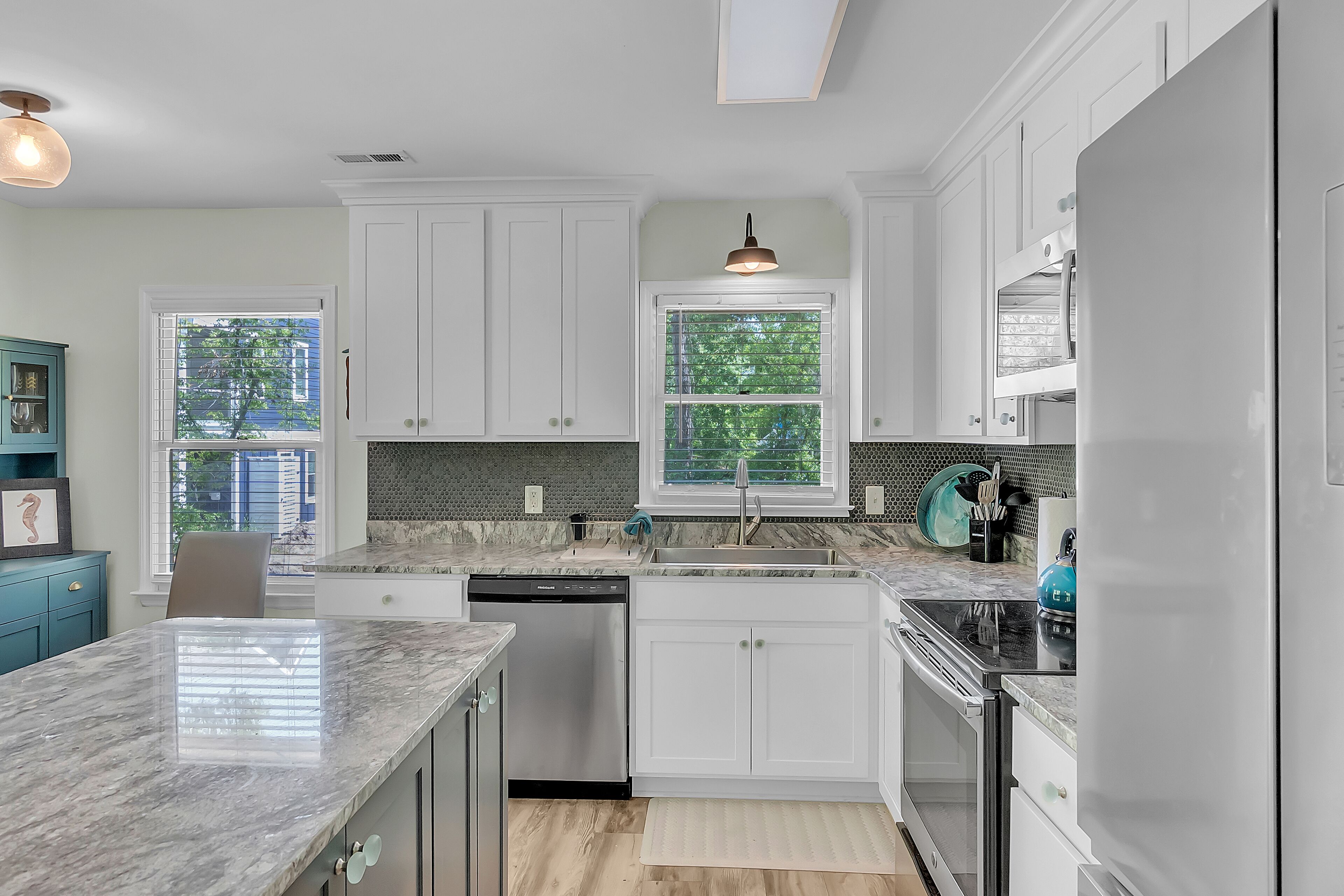 A modern kitchen with white cabinets, a granite countertop, and a built-in oven.