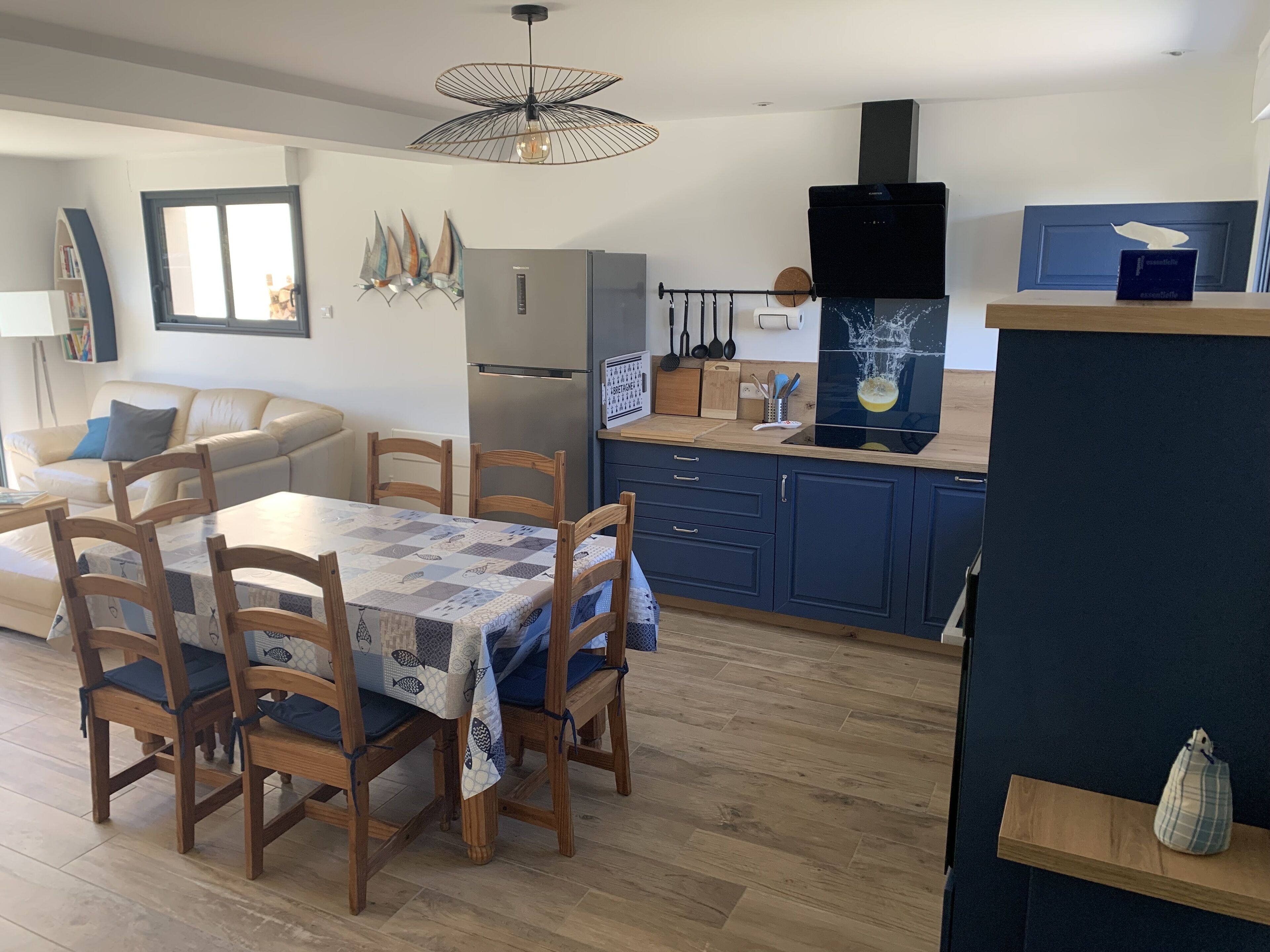 A modern kitchen with a dining area, featuring a wooden table, chairs, and a blue cabinet.
