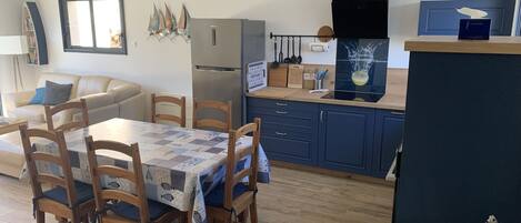 A modern kitchen with a dining area, featuring a wooden table, chairs, and a blue cabinet.