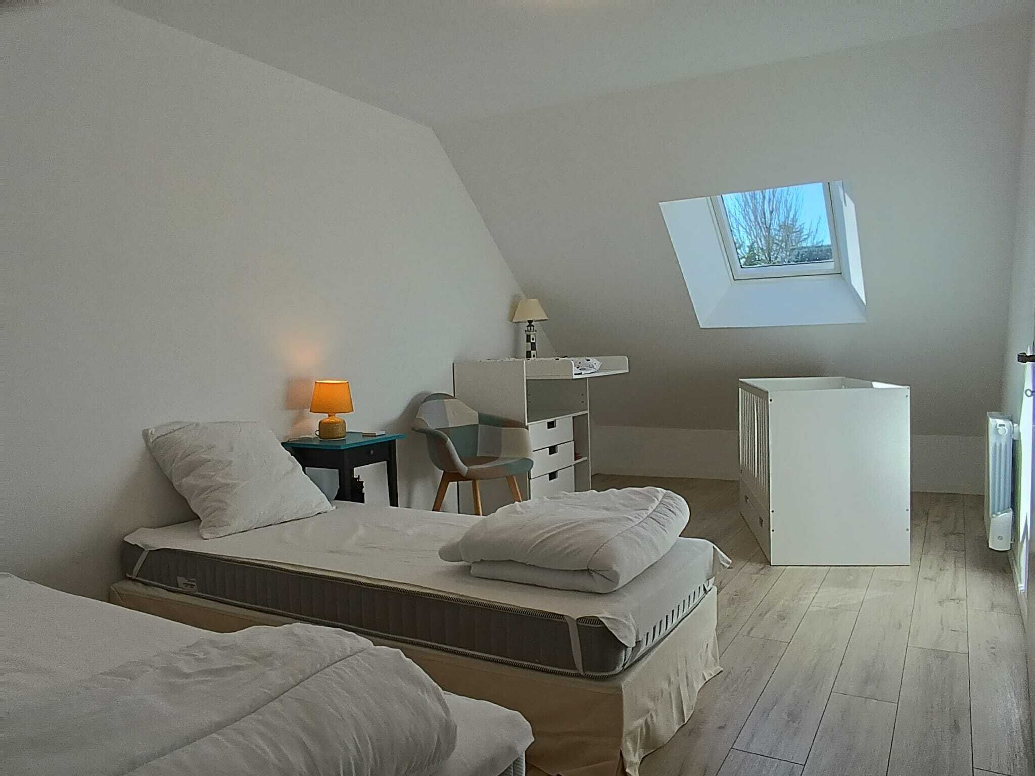 Un dormitorio con cama tipo litera, un escritorio con silla, un radiador pequeño y una ventana con vistas.