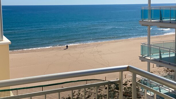A beach view from a balcony with a clear sky.