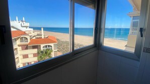 A room with a view of a beach and ocean through large windows.