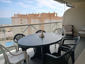 A balcony with a round table and chairs, overlooking a residential area and the sea. - Mar Azul  6º, Solo Familias! (Playa Xeraco)