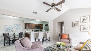 A spacious living room with a sofa, a coffee table, and a dining area with chairs and a table.