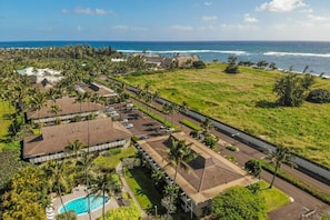 An aerial view of a resort with multiple buildings, a swimming pool, and a beachfront.