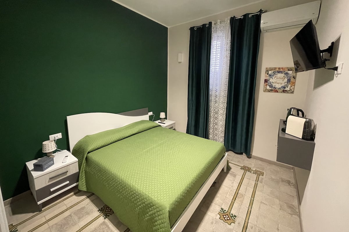 A bedroom with a bed, nightstand, and a TV mounted on the wall.