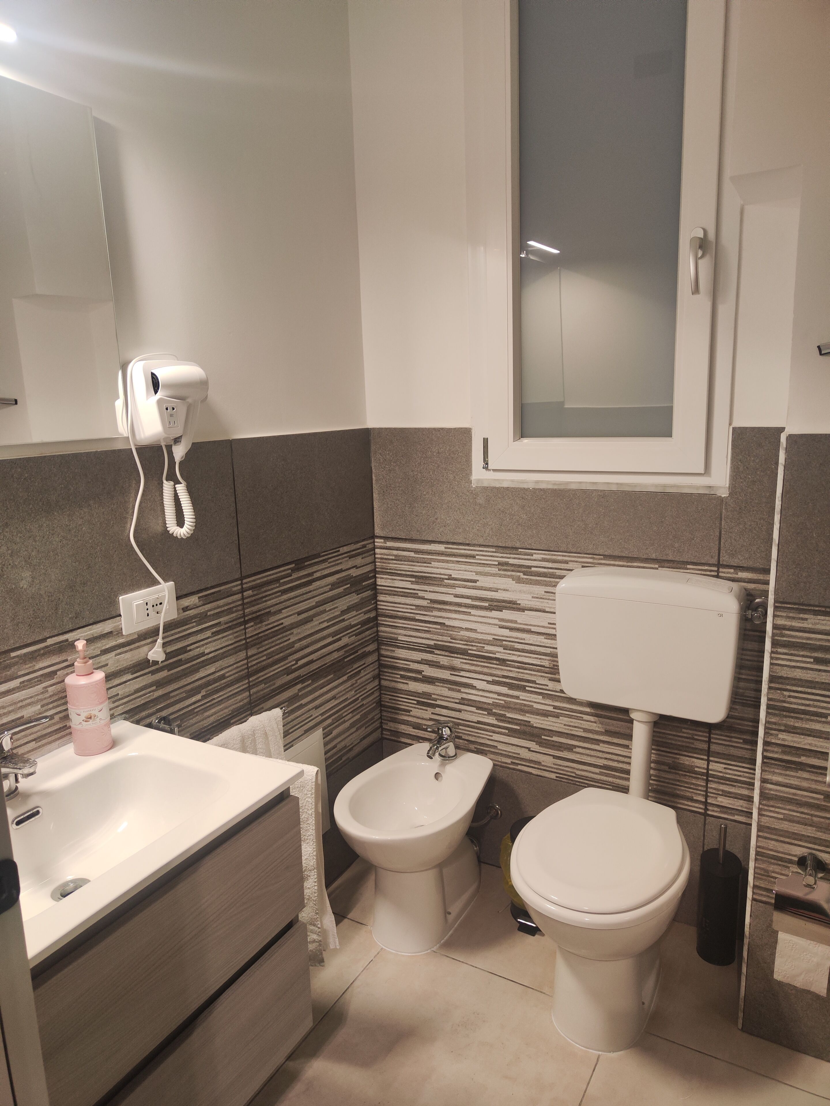 Ein Badezimmer mit Waschbecken, Bidet, Toilette und einem Fön an einer Wandsteckdose.