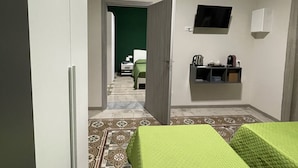A hotel room with a bed, a TV mounted on the wall, and a small shelf with items. - Soffio di Relax (Palermo)
