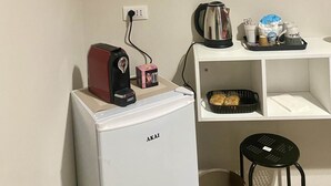 A compact kitchenette with a refrigerator, coffee maker, kettle, and a small shelf with a tray of items. - Soffio di Relax (Palermo)