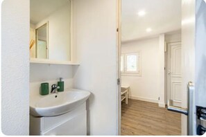 Bathroom features a sink and mirror, with a door and wooden floor.