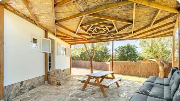 Un patio cubierto con suelo de piedra, una mesa de madera y un sofá.