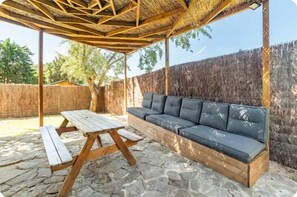 Relax in a serene outdoor space with a sofa, wooden table, and benches.