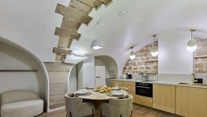 A compact kitchen with a round dining table, two chairs, a built-in oven, and a sink.