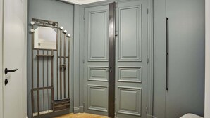 A room with a grey door, a mirror with lights, and a wooden floor. - Superb new flat Notre Dame de Paris (Paris)