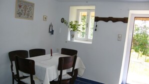 Un comedor con una mesa preparada para cuatro, una ventana con vistas y una puerta que da al exterior.