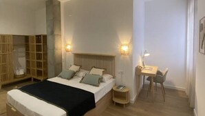 A bedroom with a bed, bedside tables, a desk, and a chair. - A (VA070.2.9) TH Mediterranean Suites 9 (Valencia / València)