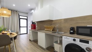 A modern kitchen with a washing machine, a microwave, and a sink.