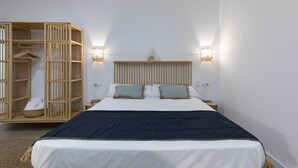 A bedroom with a bed, a wooden wardrobe, and two wall-mounted lights.