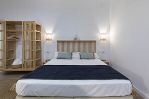 A bedroom with a bed, a wooden wardrobe, and two wall-mounted lights.