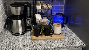 Eine Küche mit weißen Schränken, einer Kaffeemaschine, einem Becherhalter und einem Wasserspender.