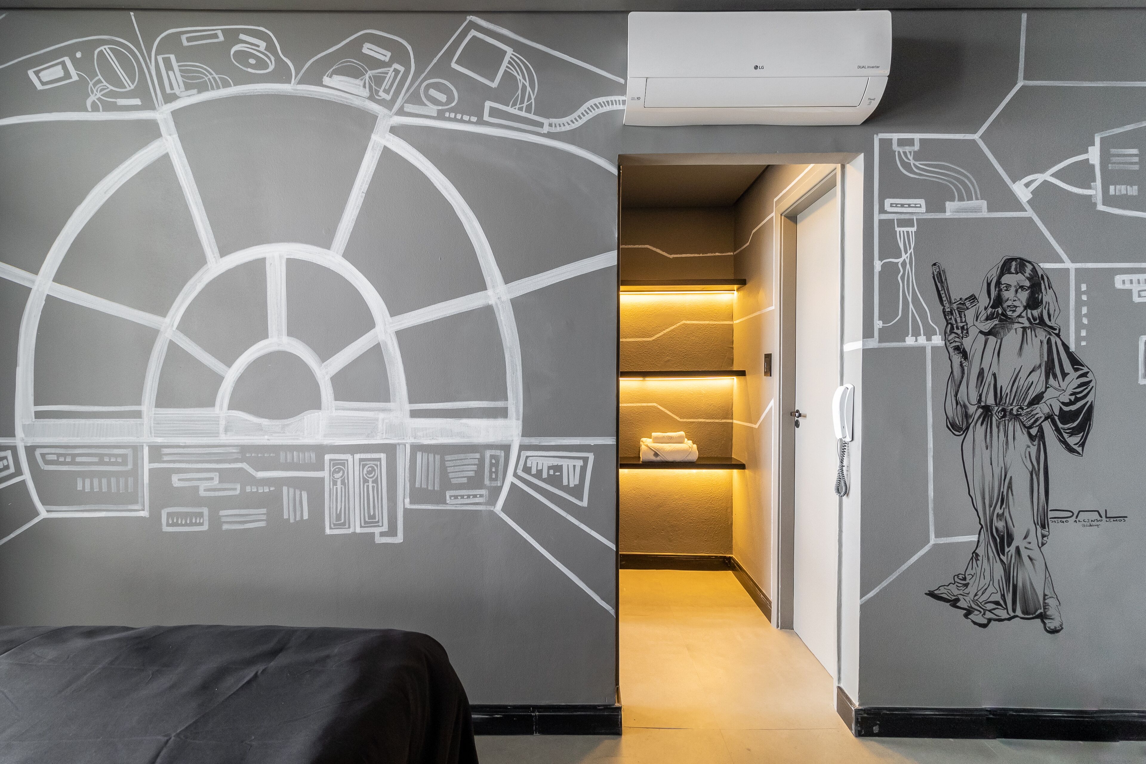 A hotel room with a large wall mural, a bed, and a hallway leading to a reception area.