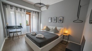A modern bedroom with a bed, bedside tables, a desk, and a hanging light fixture. - Rhome Vintage Holidays San Pietro (Rome)