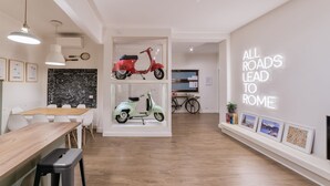 A modern interior with a dining area, two scooters displayed in glass cases, and a motivational wall sign. - Rhome Vintage Holidays San Pietro (Rome)