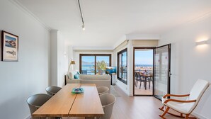 Ein moderner Essbereich mit Holztisch und Stühlen, einer Couch und Blick ins Freie.