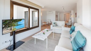 Ein modernes Wohnzimmer mit Flachbildfernseher, weißem Sofa und Couchtisch.