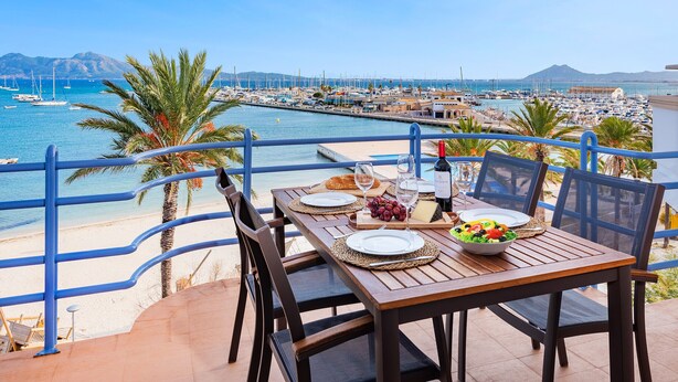 Ein Tisch ist für das Essen gedeckt, mit Blick auf einen Yachthafen und einen Strand.