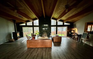 Un salon spacieux doté d’une cheminée, de grandes fenêtres et d’un plafond haut.