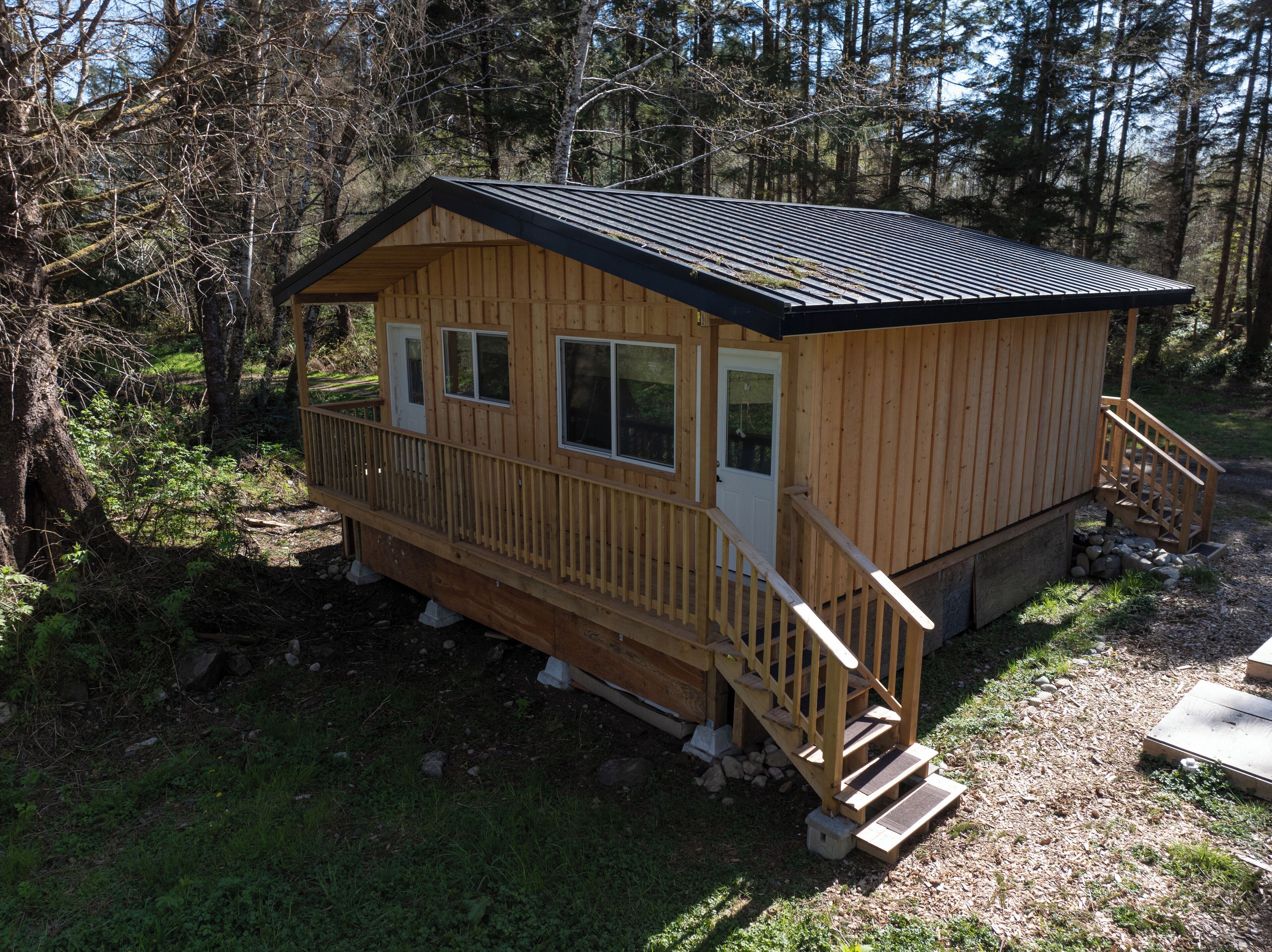 A wooden cabin with a balcony, a front door, and a staircase leading to a deck.
