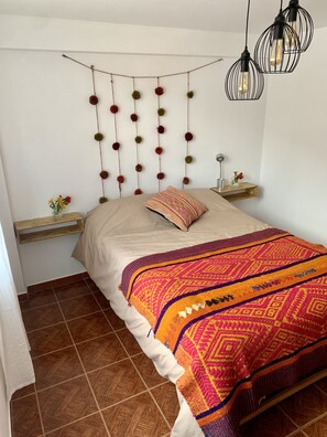 Cozy retreat with a patterned throw blanket, nightstands, and a vase with flowers.
