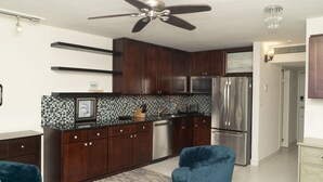 Une cuisine moderne avec des meubles de couleur bois foncé, des appareils électroménagers en acier inoxydable et un ventilateur de plafond.