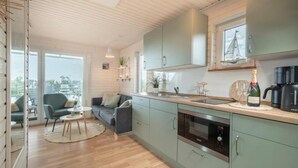 A modern kitchen with a large window, a built-in oven, and a coffee machine. - Hausboot Rán für 5 Pers. mit Großzügiger Dachterrasse in Kragenæs auf Lolland (Schleswig)