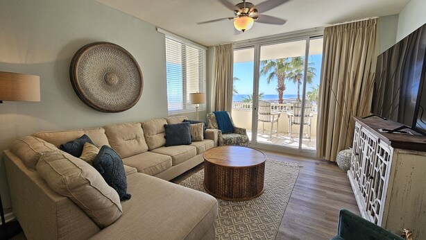 A living room with a sofa, a coffee table, and a view of the ocean through large sliding doors.