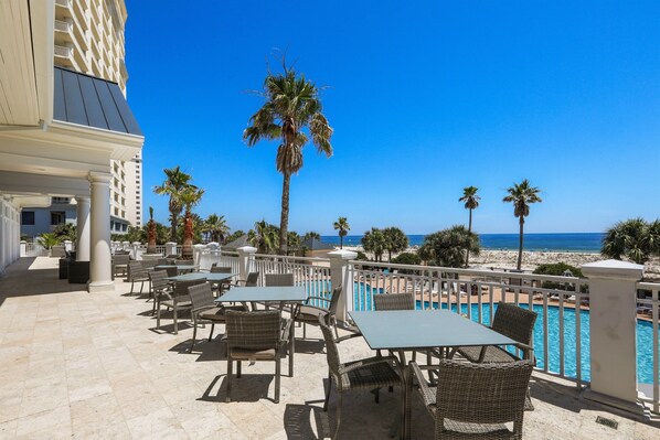 A rooftop pool area with outdoor seating and a view of the beach and ocean.