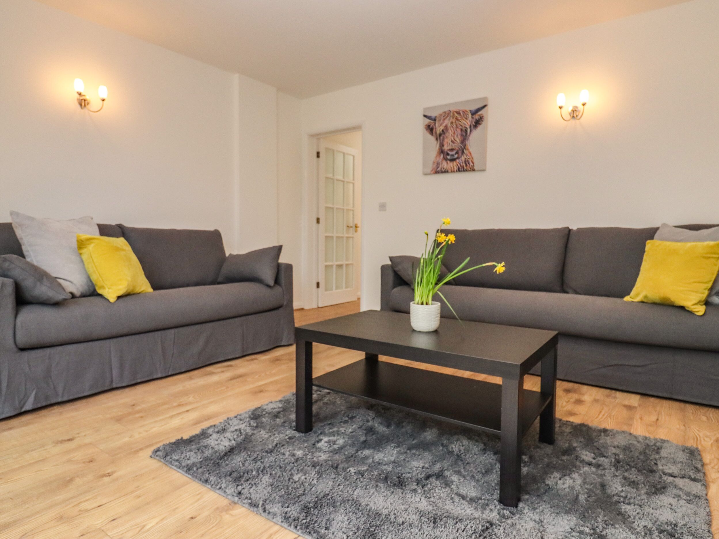 A modern living room with two grey sofas, a black coffee table, and a small potted plant.