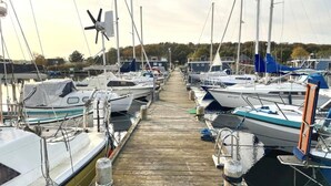 A marina with multiple boats docked along a wooden pier.