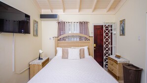 Een netjes opgemaakt slaapkamer met een bed, nachtkastjes, een televisie en een raam met gordijnen.