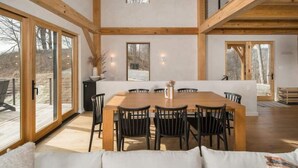 Un comedor amplio con una mesa y sillas de madera, ventanas grandes y vistas al exterior.