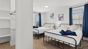 Ein Zimmer mit zwei Betten, einem Kleiderschrank und Bildern an den Wänden.