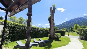 Ein Garten mit Liegestühlen, einem Weg und einem Berg im Hintergrund.