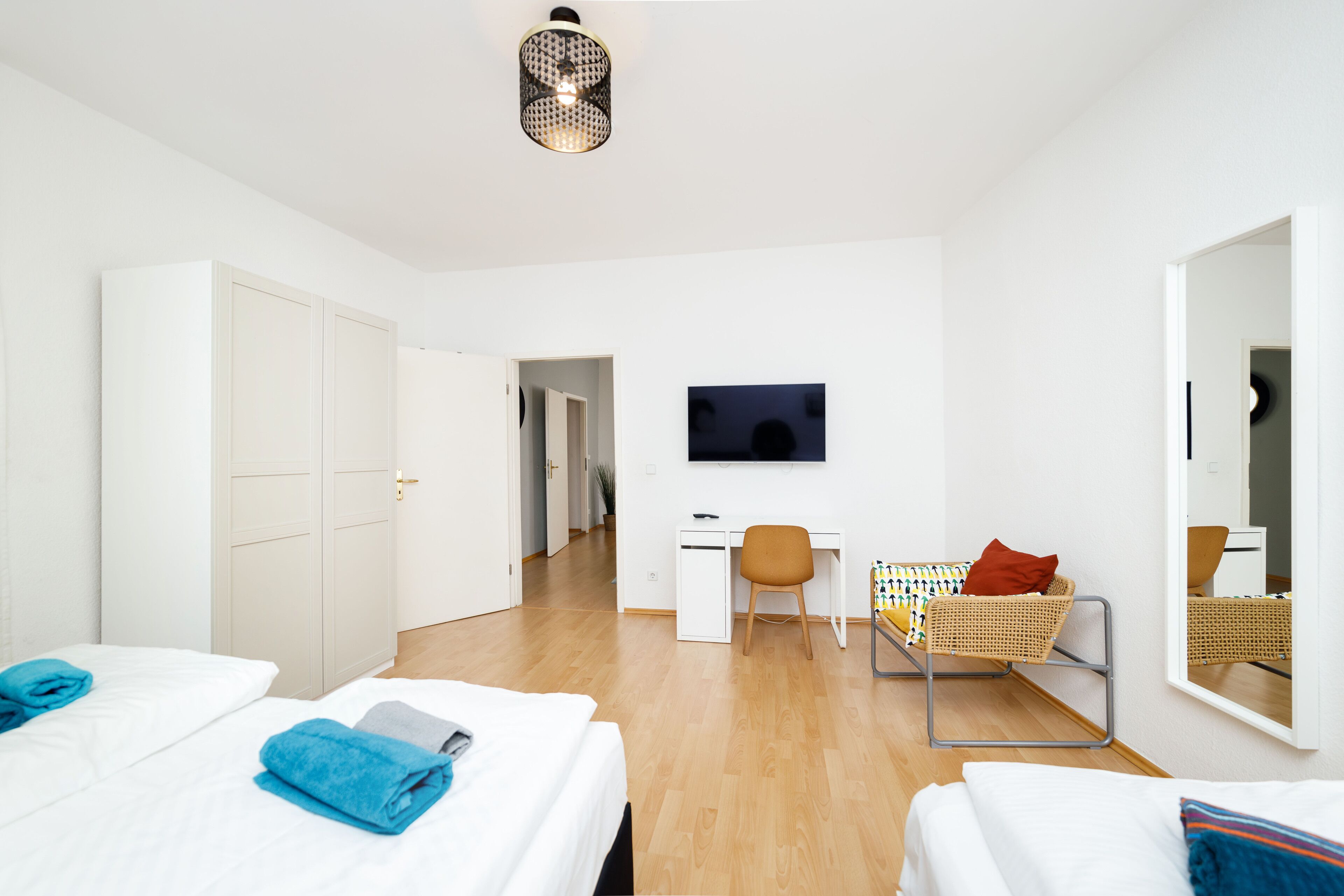 Ein Hotelzimmer mit zwei Betten, einem Schreibtisch, einem Stuhl, einem Fernseher und einem Spiegel.
