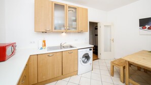 Una cocina compacta con armarios de madera, lavadora, microondas rojo y encimera blanca.