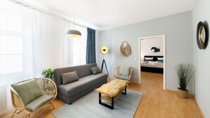 Una sala moderna con un sofá gris, una mesa de centro de madera y una silla de mimbre.