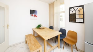Un comedor con una mesa de madera, dos sillas, un banco y un cuadro colgado en la pared con cerezas.