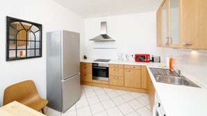 Una cocina moderna con electrodomésticos de acero inoxidable, armarios de madera y piso de baldosas.
