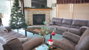 Un salon avec une cheminée, un sapin de Noël et deux canapés.