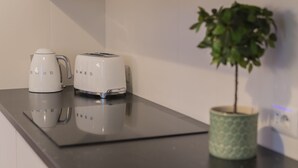 A kitchen counter with two white electric kettles and a toaster, a green potted plant, and a power outlet. - Vintage Apartment Giuliana (Rome)